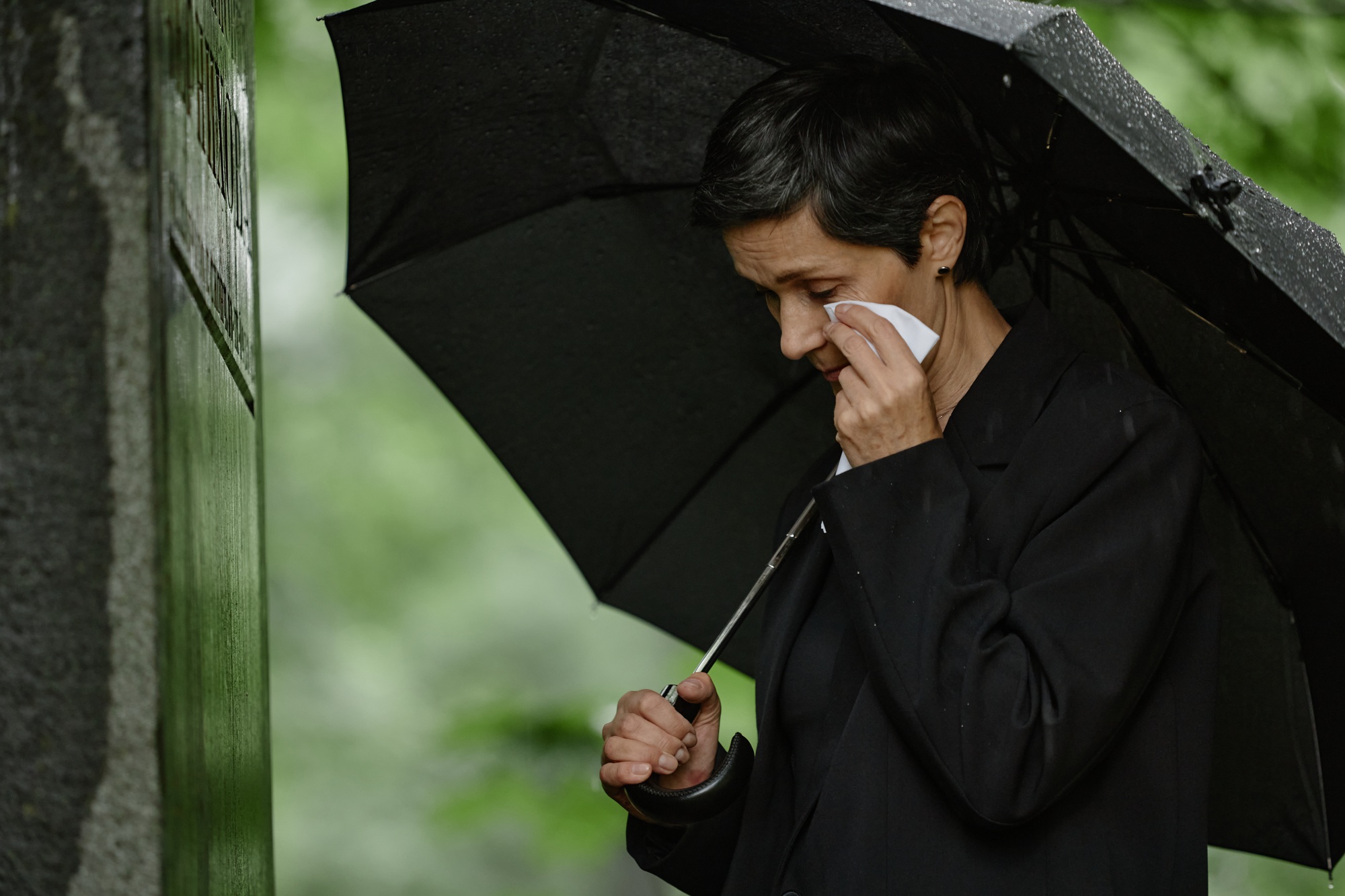 Woman Grieving at Grave Wiping Tears with Handkerchief under Umbrella at Cemetery